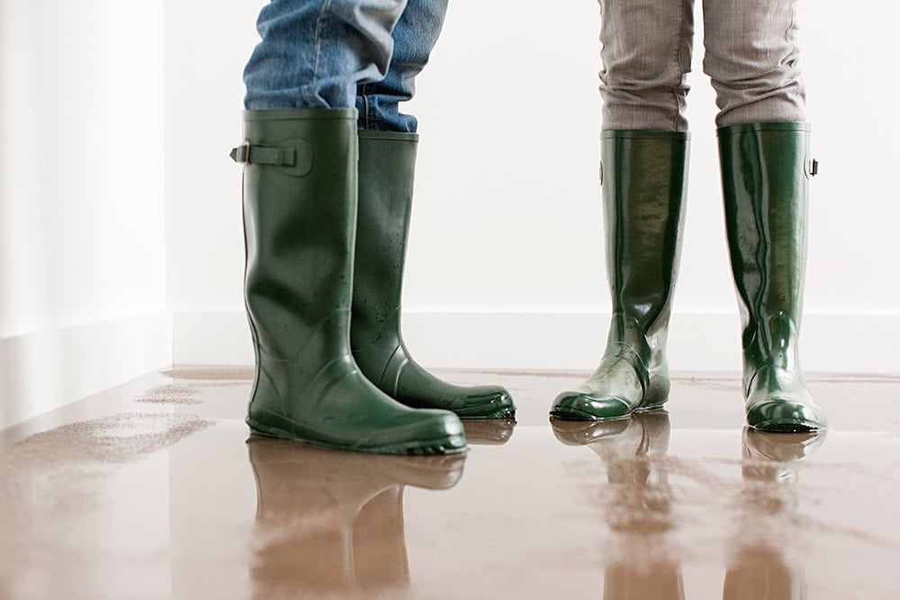 people standing in their flooded house because their furnace is leaking