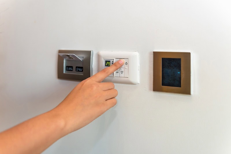 a person adjusting the thermostat for the heat pump