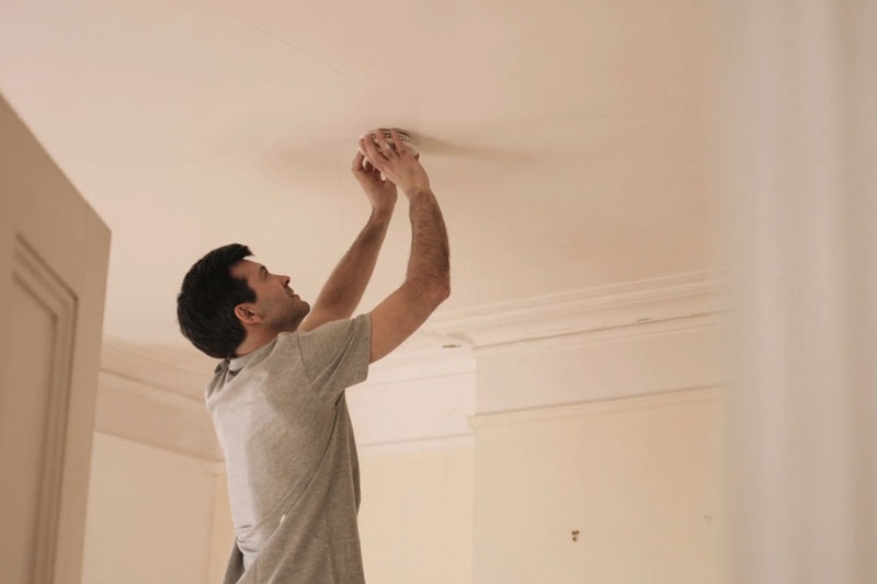 man replacing the batteries in a smoke detector