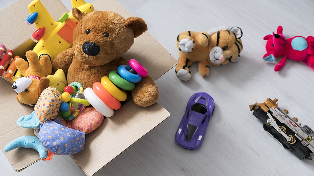 Box of toys on the floor with a teddy bear in a box.